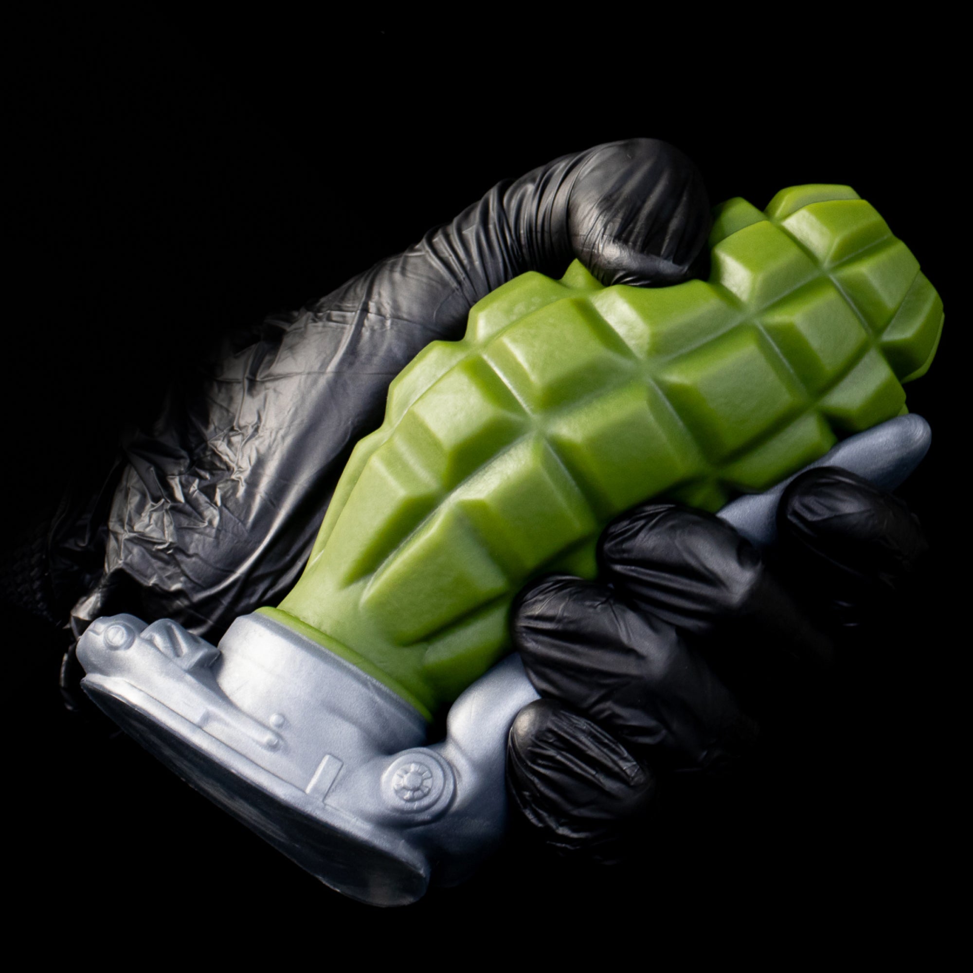 Gloved hand holding a Swallow Bomb anal plug with the rigid safety-bar handle held clear of the flat base